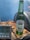A Heineken Silver beer bottle stands on a wooden surface next to a digital thermometer. The thermometer displays several temperature readings. The background is a soft blue color, enhancing the refreshing theme.
