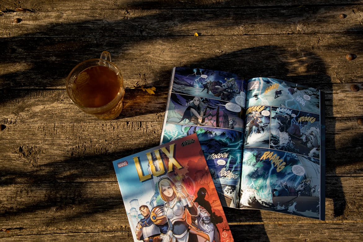 Stack of colorful comic books and graphic novels arranged on a wooden table, showcasing diverse cover art