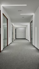 A commercial hallway featuring fresh paint, new carpet, and updated wall systems.