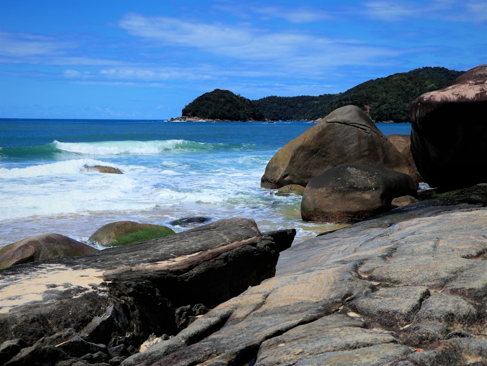 a rocky beach with a body of water in the background