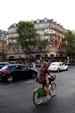 a person riding a bicycle in Paris with cars and buildings in the background