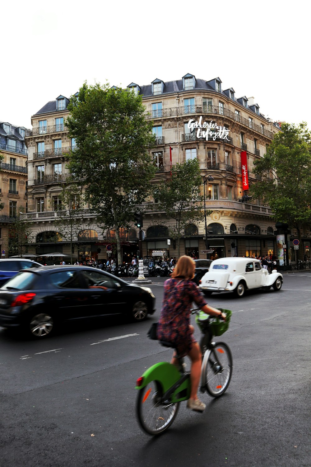 Eine Person, die auf einer Straße mit Autos und Gebäuden im Hintergrund Fahrrad fährt