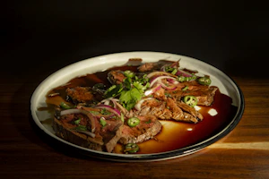 Grilled steak topped with vibrant green chimi gel served on a ceramic plate
