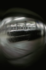 A blurred image depicting a large number of shopping carts lined up under bright fluorescent lights in a structured setting, possibly a warehouse or a storage area. The background and foreground are out of focus, creating a distorted effect.