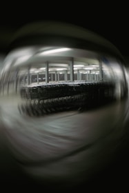 A blurred image depicting a large number of shopping carts lined up under bright fluorescent lights in a structured setting, possibly a warehouse or a storage area. The background and foreground are out of focus, creating a distorted effect.