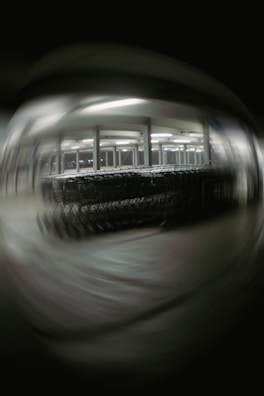 A blurred image depicting a large number of shopping carts lined up under bright fluorescent lights in a structured setting, possibly a warehouse or a storage area. The background and foreground are out of focus, creating a distorted effect.