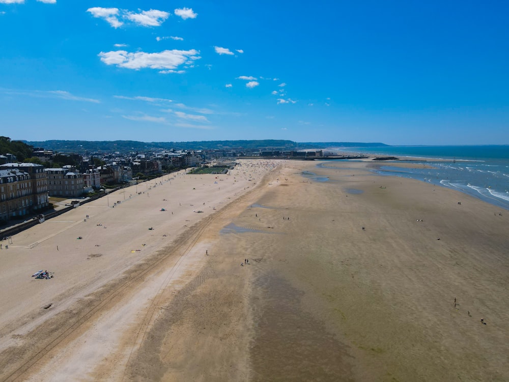 a sandy beach with a fence and buildings on the side