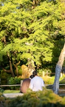 A couple sitting close together on a park bench, smiling and enjoying nature.