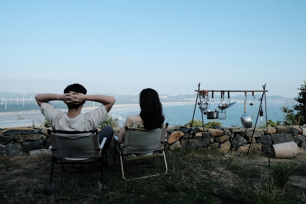 a man and woman sitting on a bench in front of a body of water