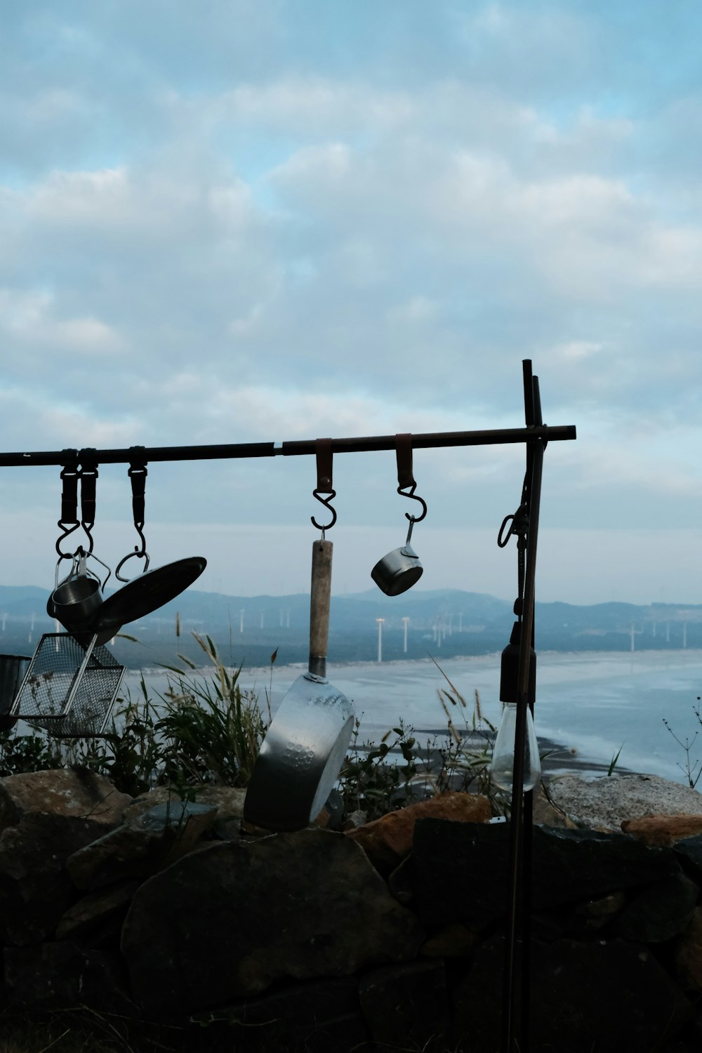 a group of bells on a pole by a body of water