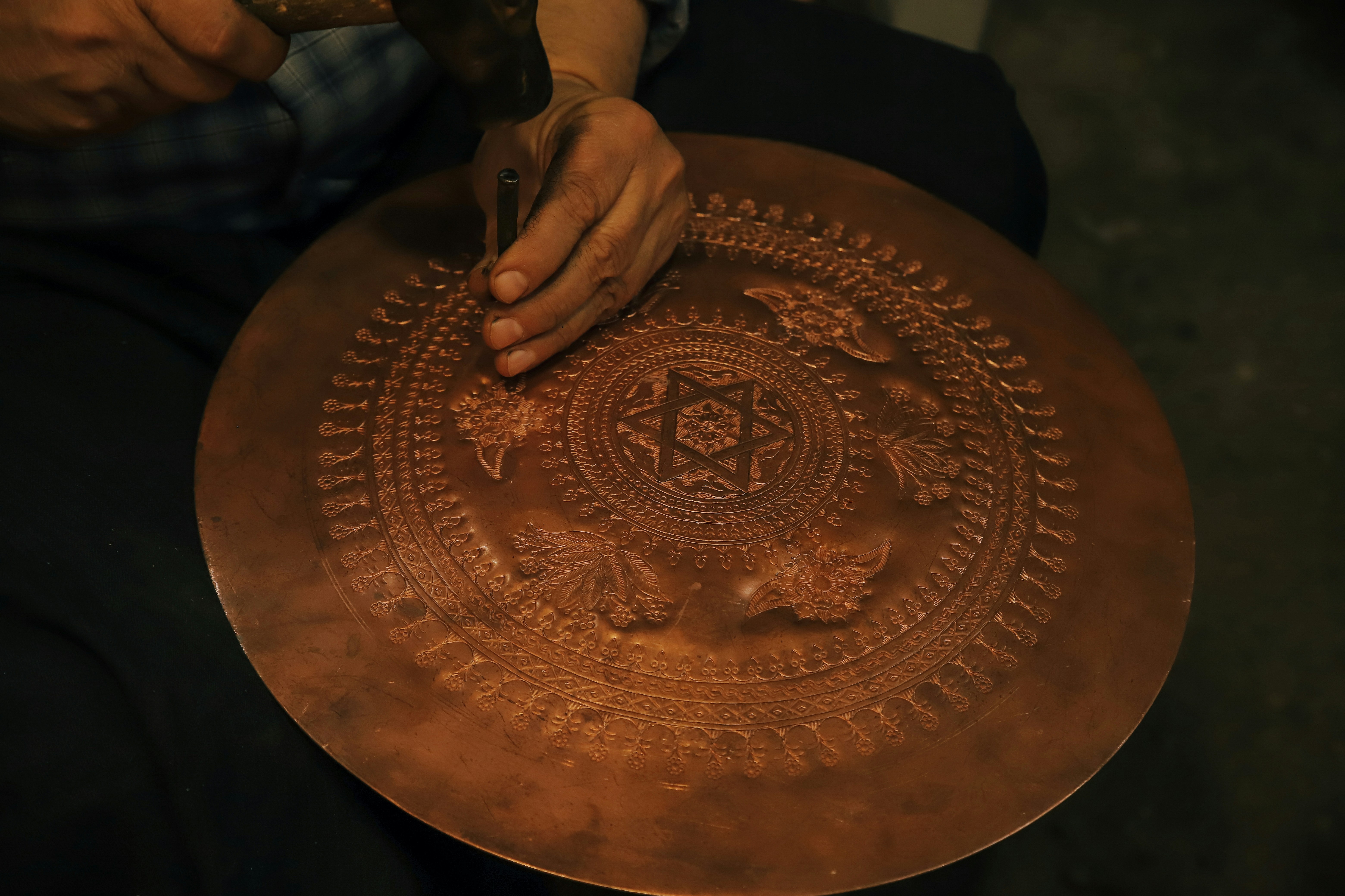A close-up shot of ancient copper plates with intricate Tamil script, being carefully handled by gloved hands during a formal handover ceremony between two officials.