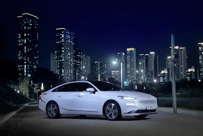 A sleek modern car parked in front of a bright cityscape.
