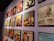 A wall features a collection of framed vinyl record covers, arranged in a neat grid. The covers showcase a variety of designs and colors, each featuring different musical artists and album titles. The overall setting appears to be in a gallery or a music-themed room.