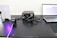 A laboratory setup includes a laser device emitting a blue light, a control box with cables, and a laptop displaying data or software. The components are arranged on a perforated optical table.