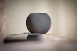 User interacting with a compact smart speaker in a modern living room.