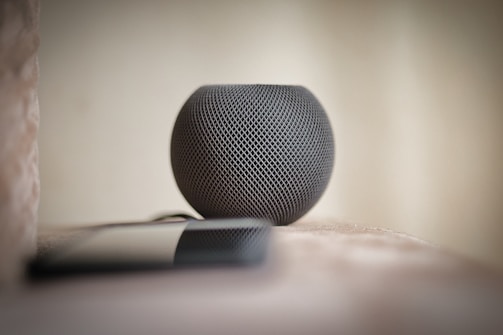 Close-up of the Urbanecho smart speaker resting on a sleek wooden table with city skyline blurred in the background.