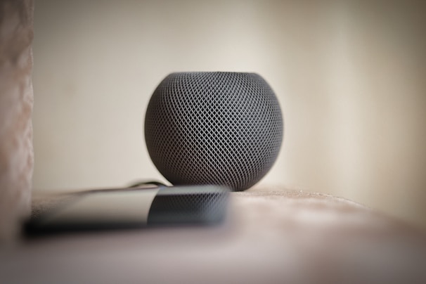 A compact smart home assistant device sitting on a kitchen counter next to a coffee mug.