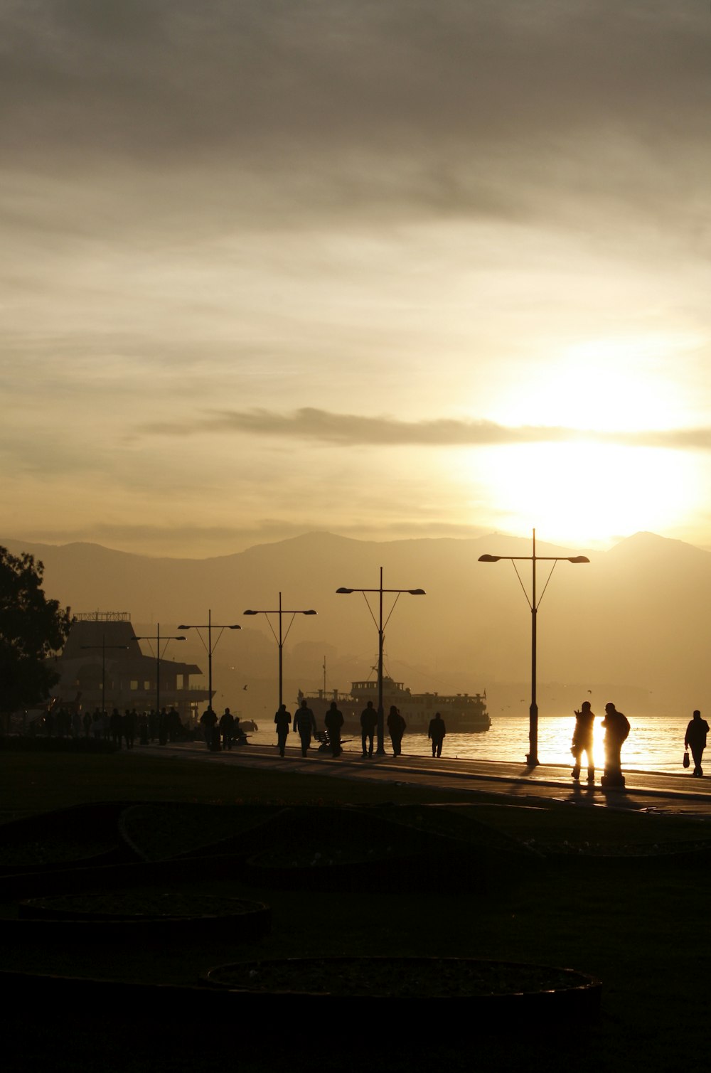 a group of people walking on a sidewalk by a body of water