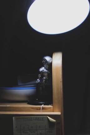 An AI robot figurine placed beside a notebook and a cup of coffee on a desk.