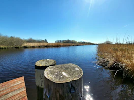 a body of water with a wood post and a wood railing