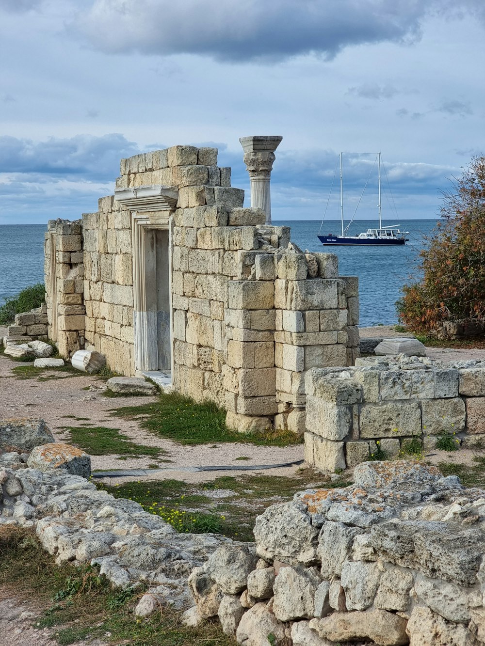 a stone building with a tower and a boat in the background