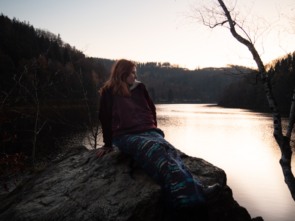 a person sitting on a rock by a river