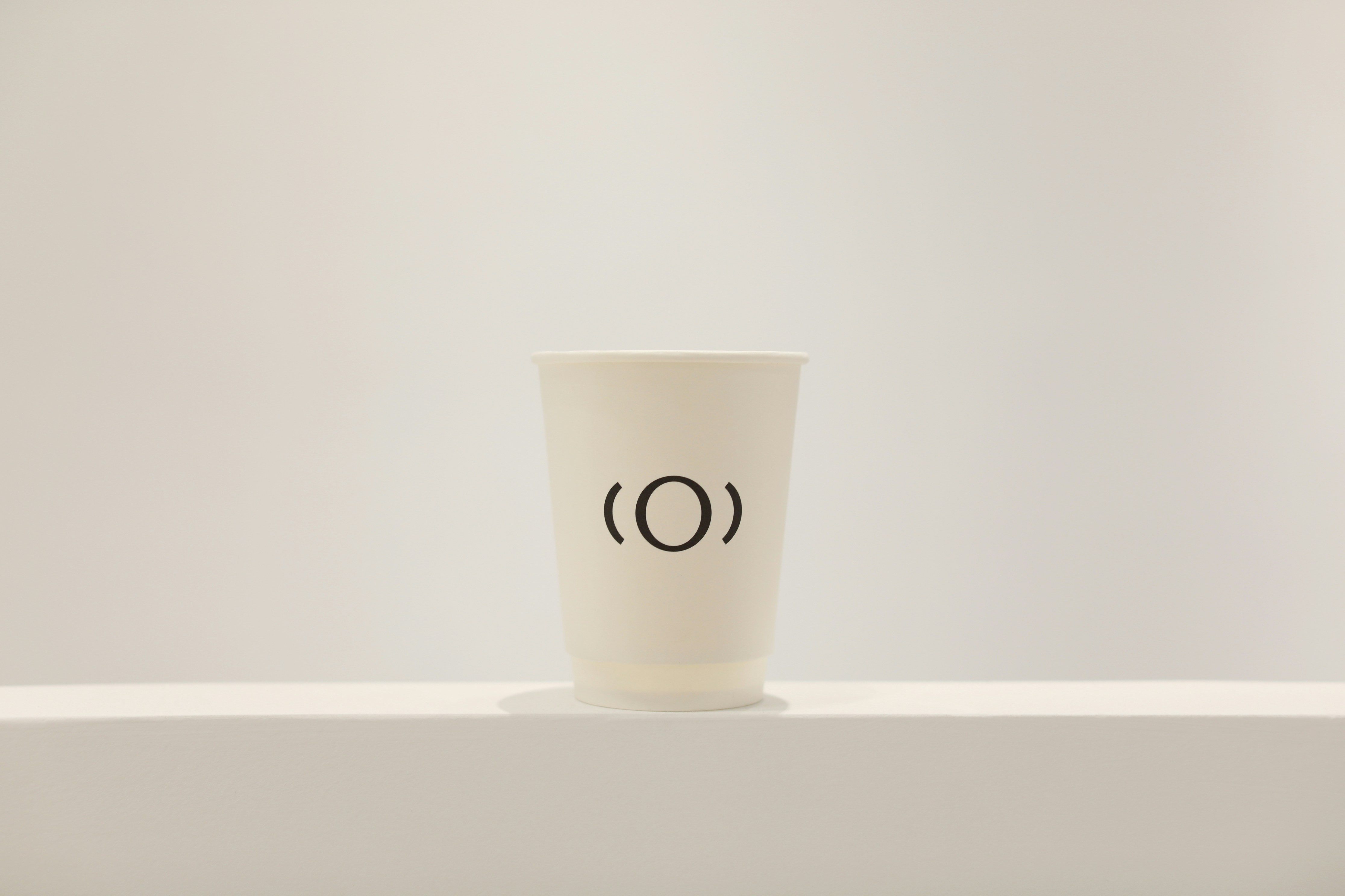 White paper cup with black circle logo on shelf