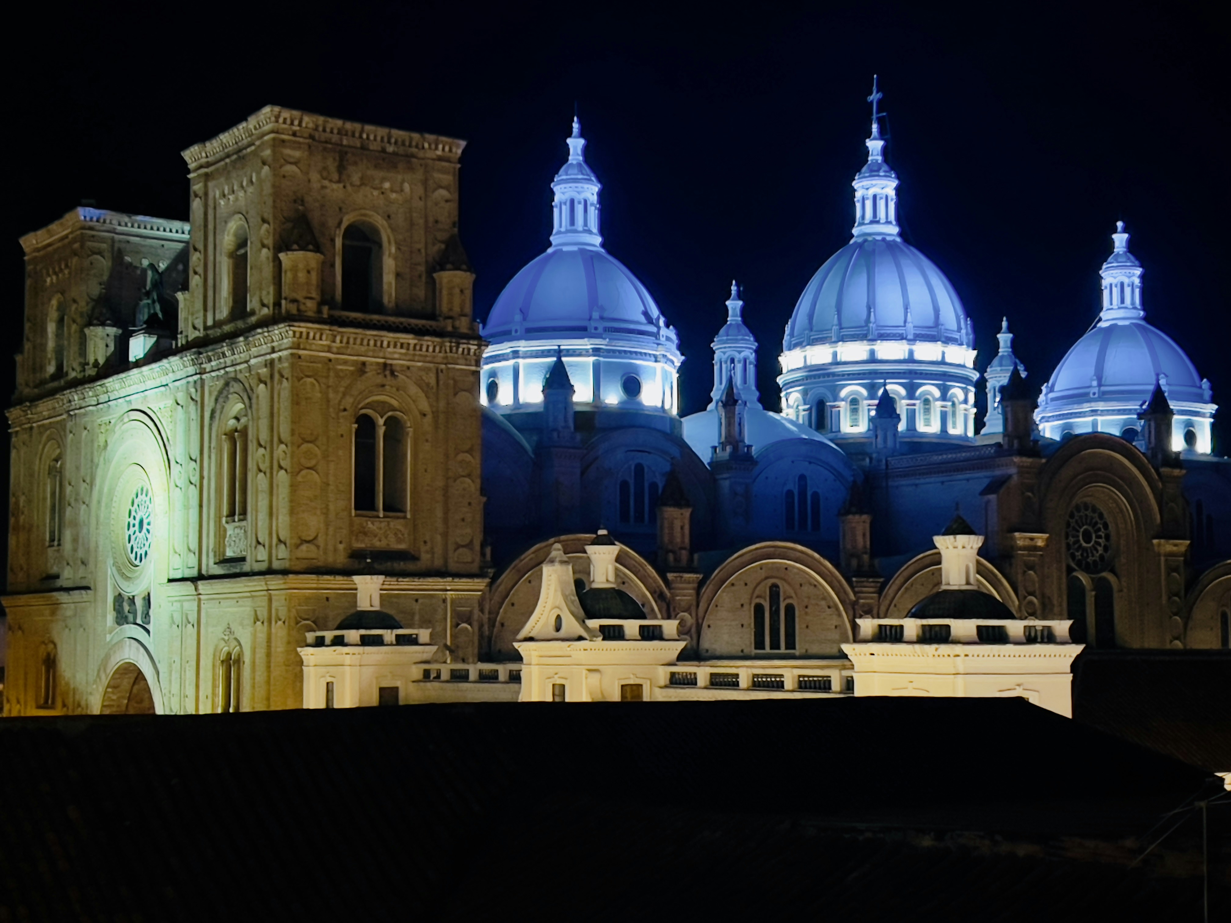 a large building with domed roofs with Cuenca in the background