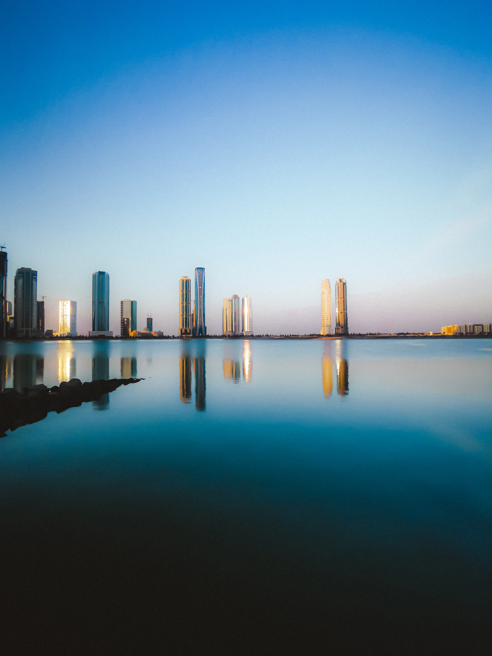 Sharjah waterfront towers reflected in still water