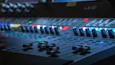 Close-up of sound mixing equipment with artistic stained glass reflections.