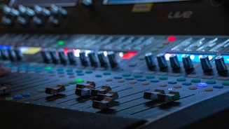 A close-up of a soundboard with colorful lights during a jingle production.