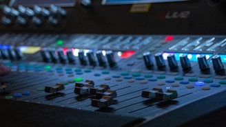 Close-up of a professional sound mixing console with colorful lights during a live event