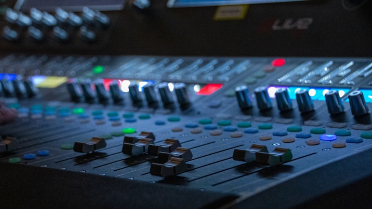 Close-up of mixing console with colorful sound levels glowing.
