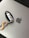 A car key fob with a metallic orange carabiner attached rests on a silver laptop with an Apple logo.