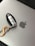 A car key fob with a metallic orange carabiner attached rests on a silver laptop with an Apple logo.