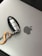 A car key fob with a metallic orange carabiner attached rests on a silver laptop with an Apple logo.