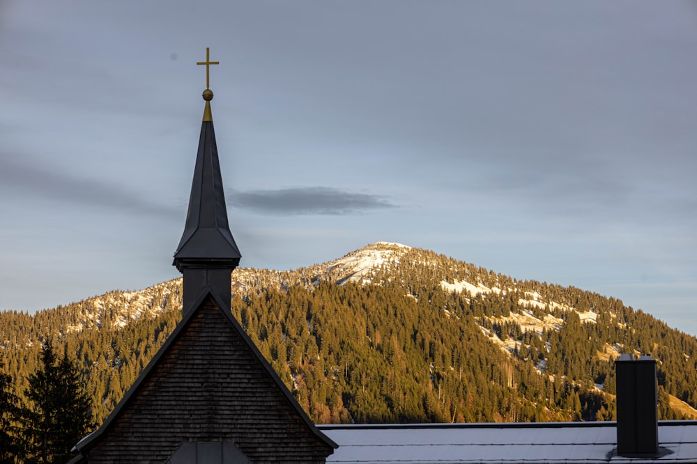 a building with a steeple and a mountain in the background