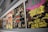 A collection of vibrant vintage album covers is displayed along a wall. The album on the right features psychedelic artwork with a cosmic theme, using bright green, pink, and yellow colors. Next to it, a monochrome jazz-themed cover from 1965 is visible, featuring black and white photos of musicians and bold text.