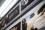 An angled view of a series of vinyl record covers displayed on a shelf, featuring a prominently visible cover with an abstract portrait and text. The colors are muted and the lighting is soft, creating a vintage atmosphere.