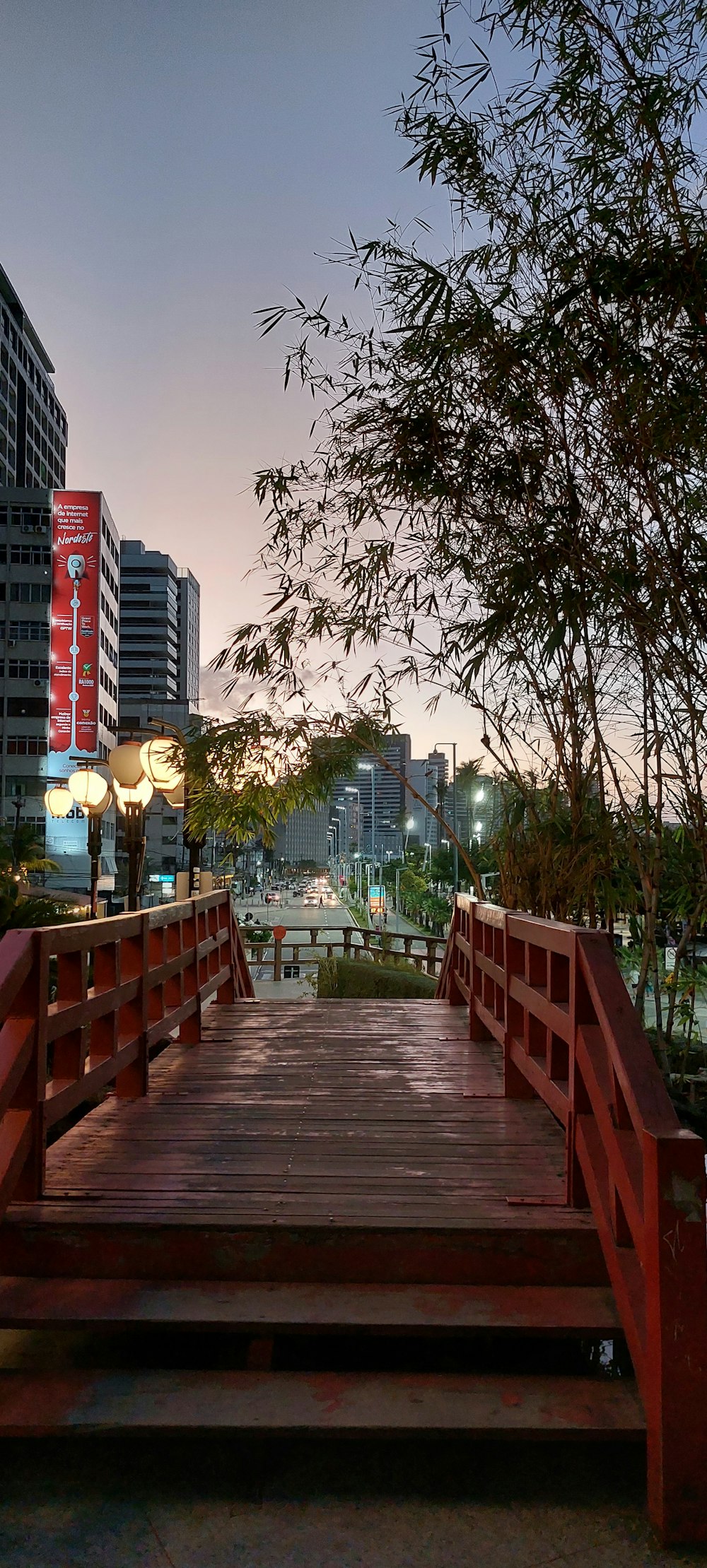 a wooden bridge with trees and buildings in the background