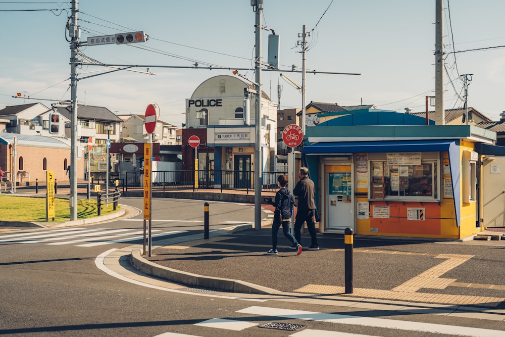 a couple of people walking down a street next to a small store