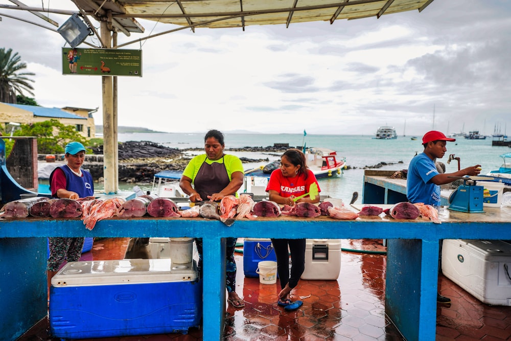 a group of people standing next to a boat full of fish