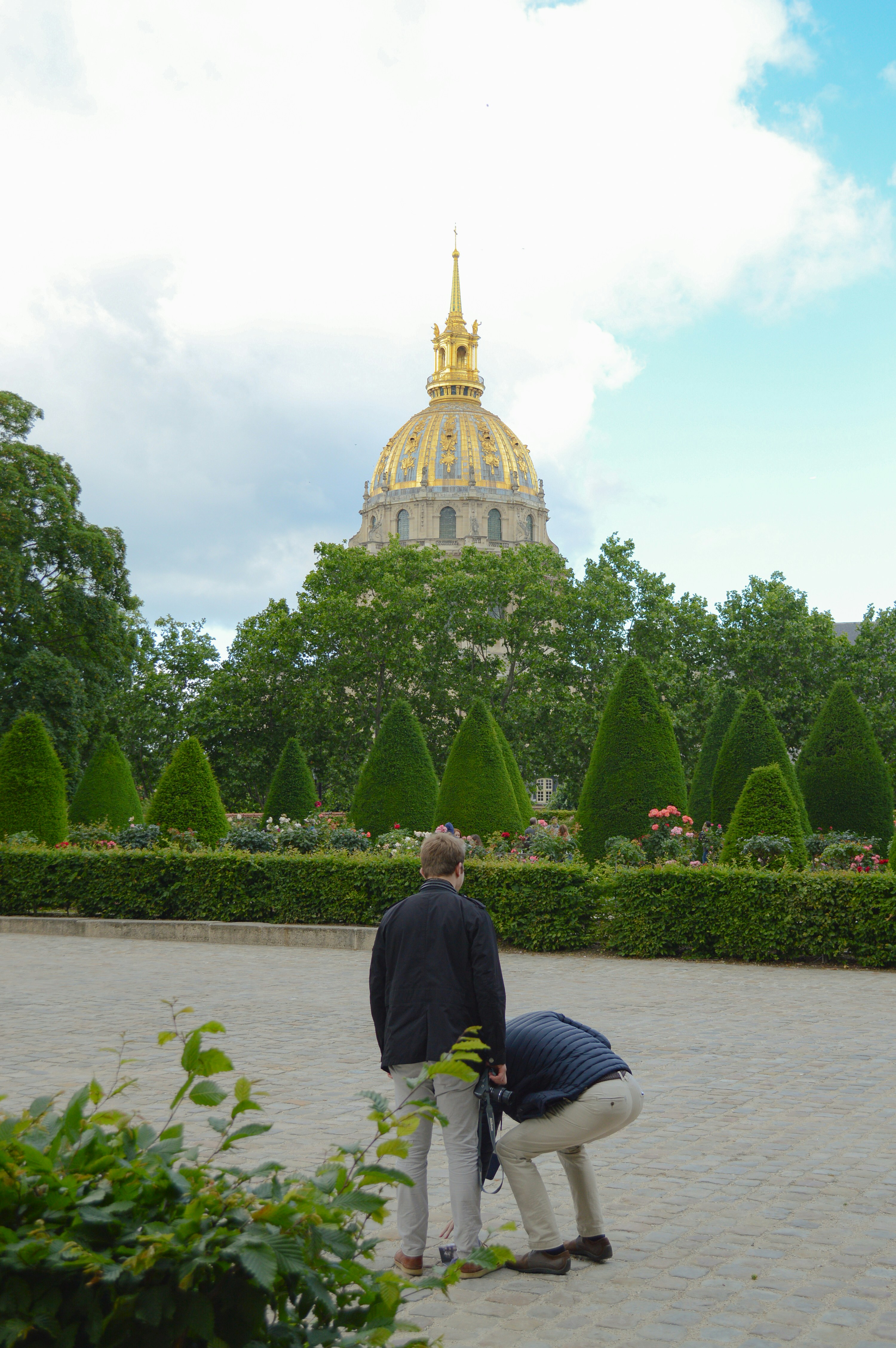 a person and a child standing in front of a building with a gold dome and trees