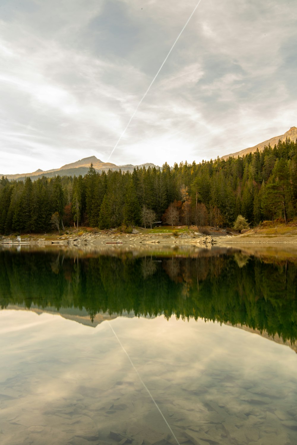 um lago com árvores e montanhas ao fundo