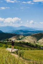 a person standing on a ledge overlooking a valley with mountains in the background