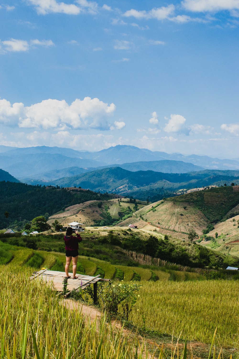 a person standing on a ledge overlooking a valley with mountains in the background