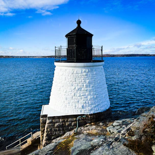 The Cap Spartel lighthouse standing tall where the Atlantic Ocean meets the Mediterranean Sea under a clear, dramatic blue sky.