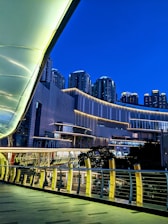 Photo of a well-lit pedestrian walkway in Canary Wharf during the evening.