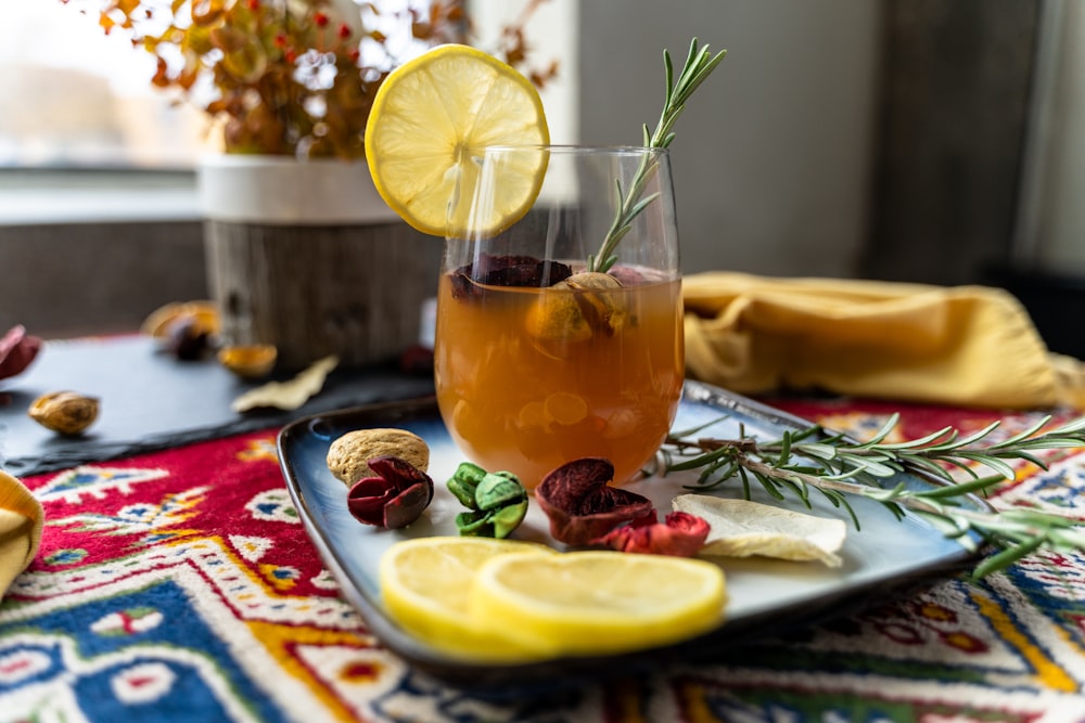 a glass with a drink and fruit on a table