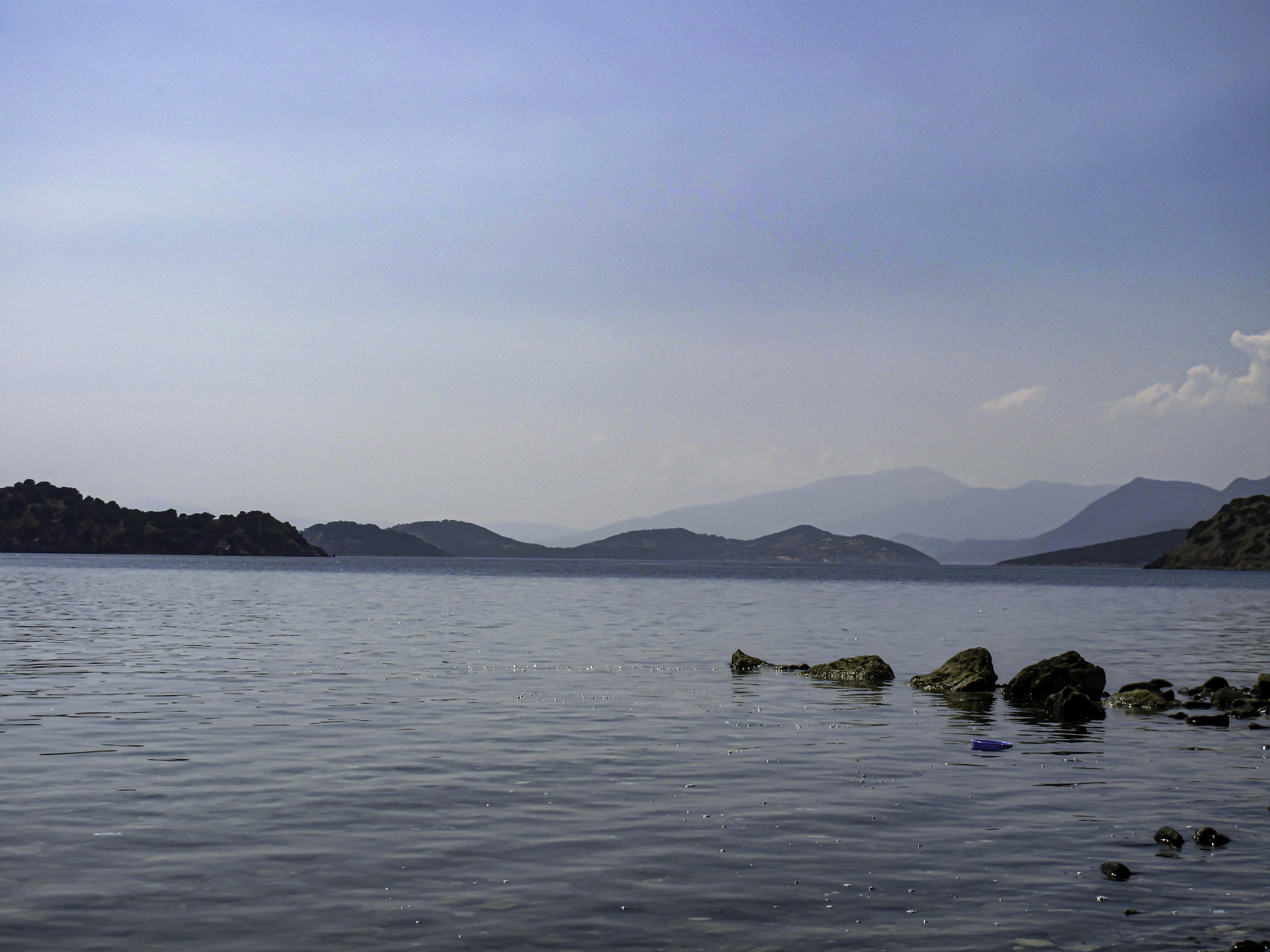 a body of water with rocks and mountains in the background, 